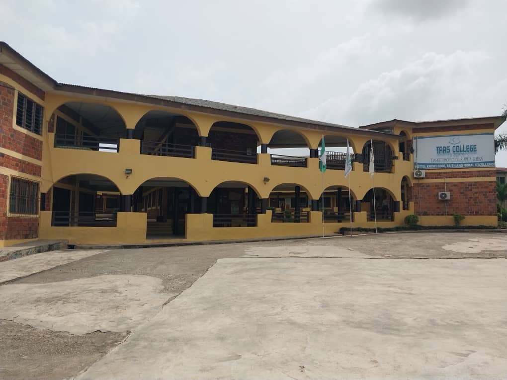 Front of TAAS College with its arched two-storey building and flags
